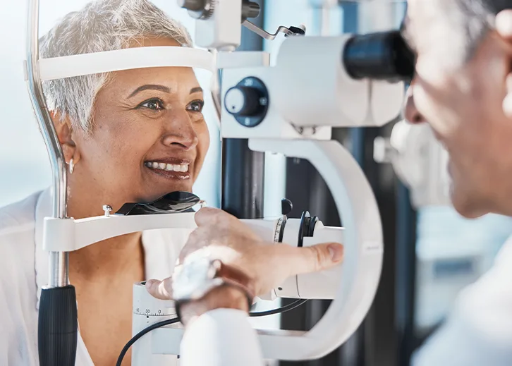 Voruntersuchung: Eine ältere Dame lässt ihre Augen untersuchen. Im Vordergrund ist ein Arzt zu sehen; die Atmosphäre wirkt sehr entspannt.